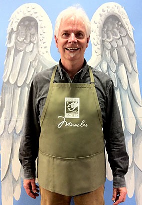 Kitchen Angels Executive Director Tony McCarty models our practical and inspiring apron!